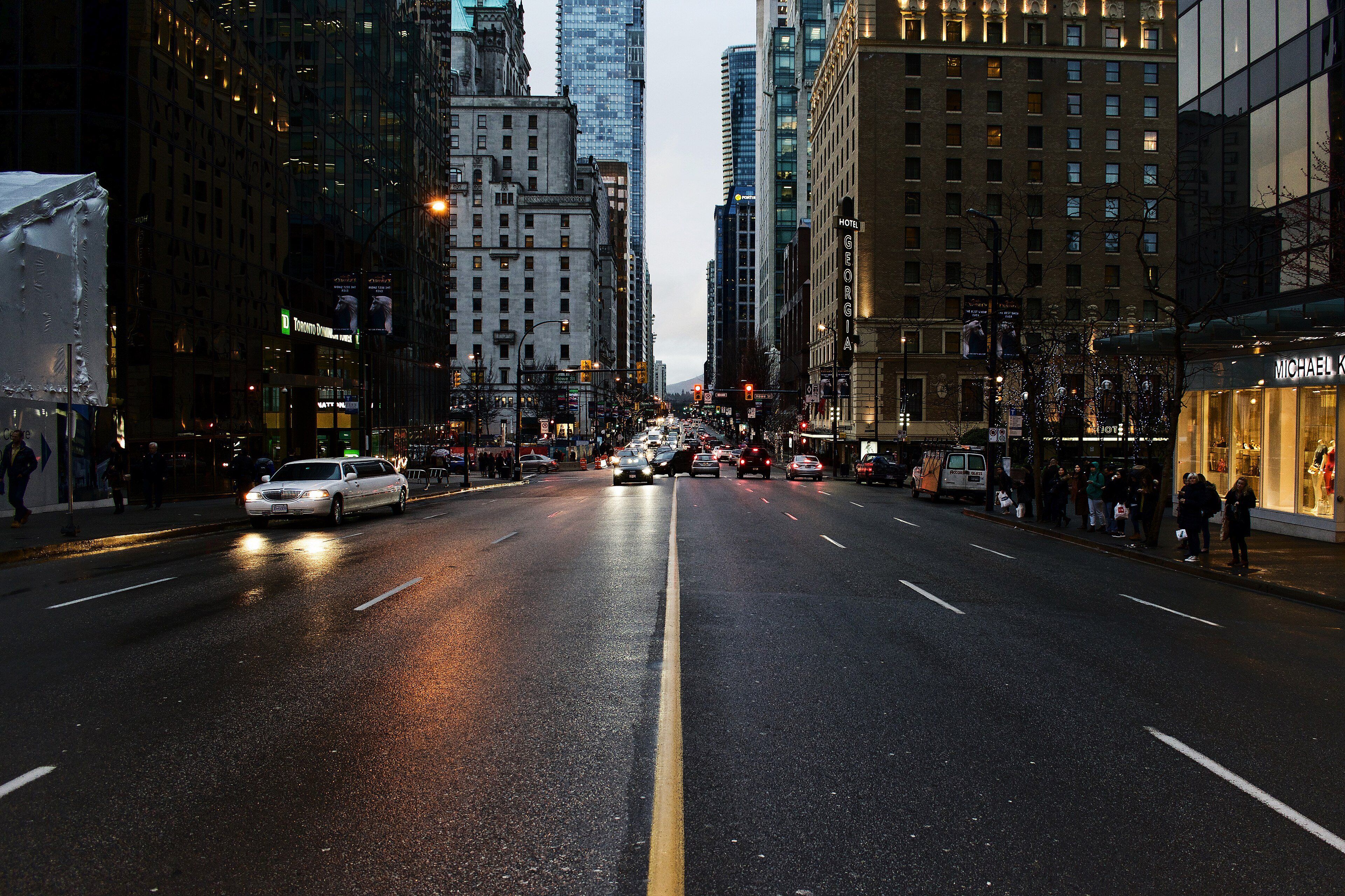 A downtown street at dusk with cars and lit windows