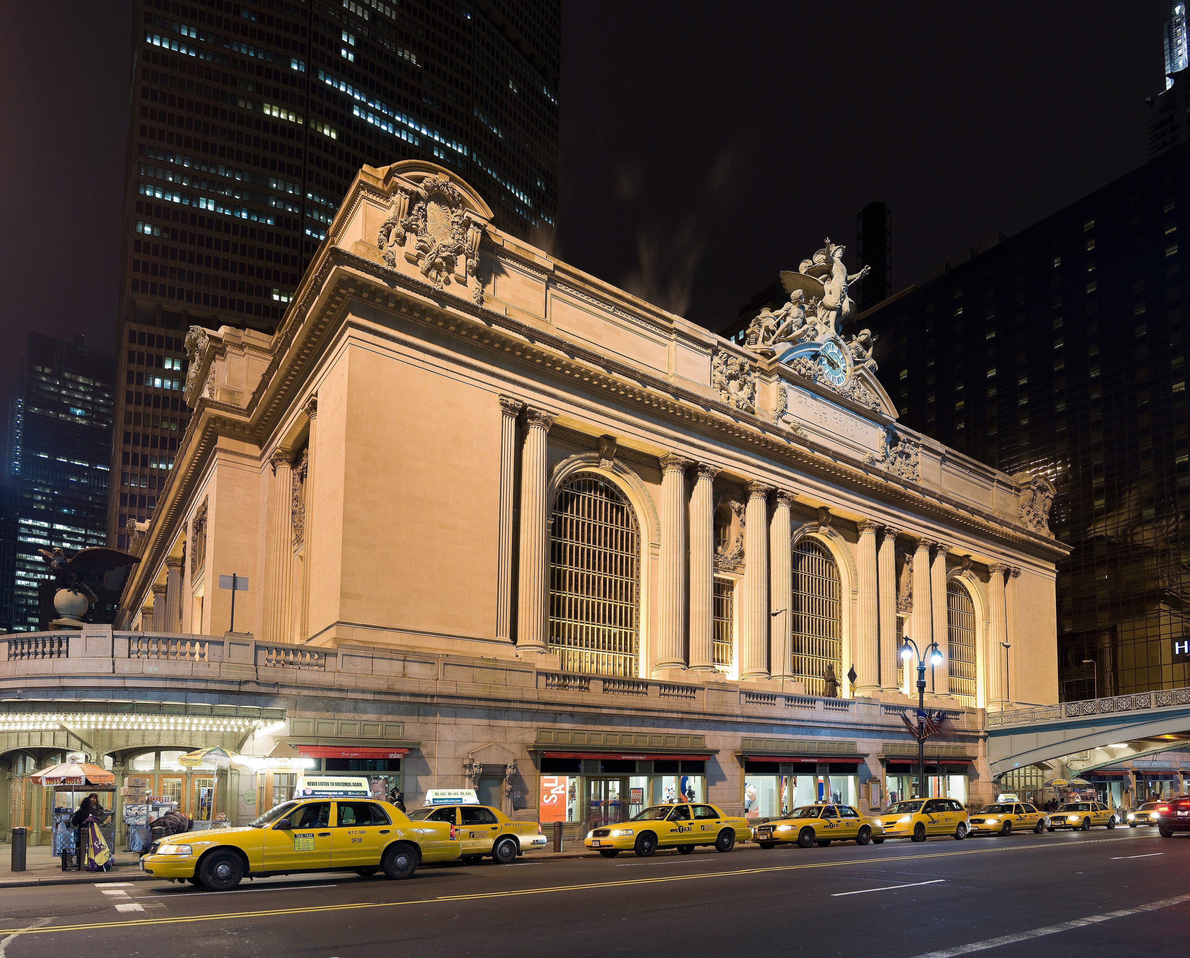 A line of yellow taxis waiting outside Grand Central Terminal at night