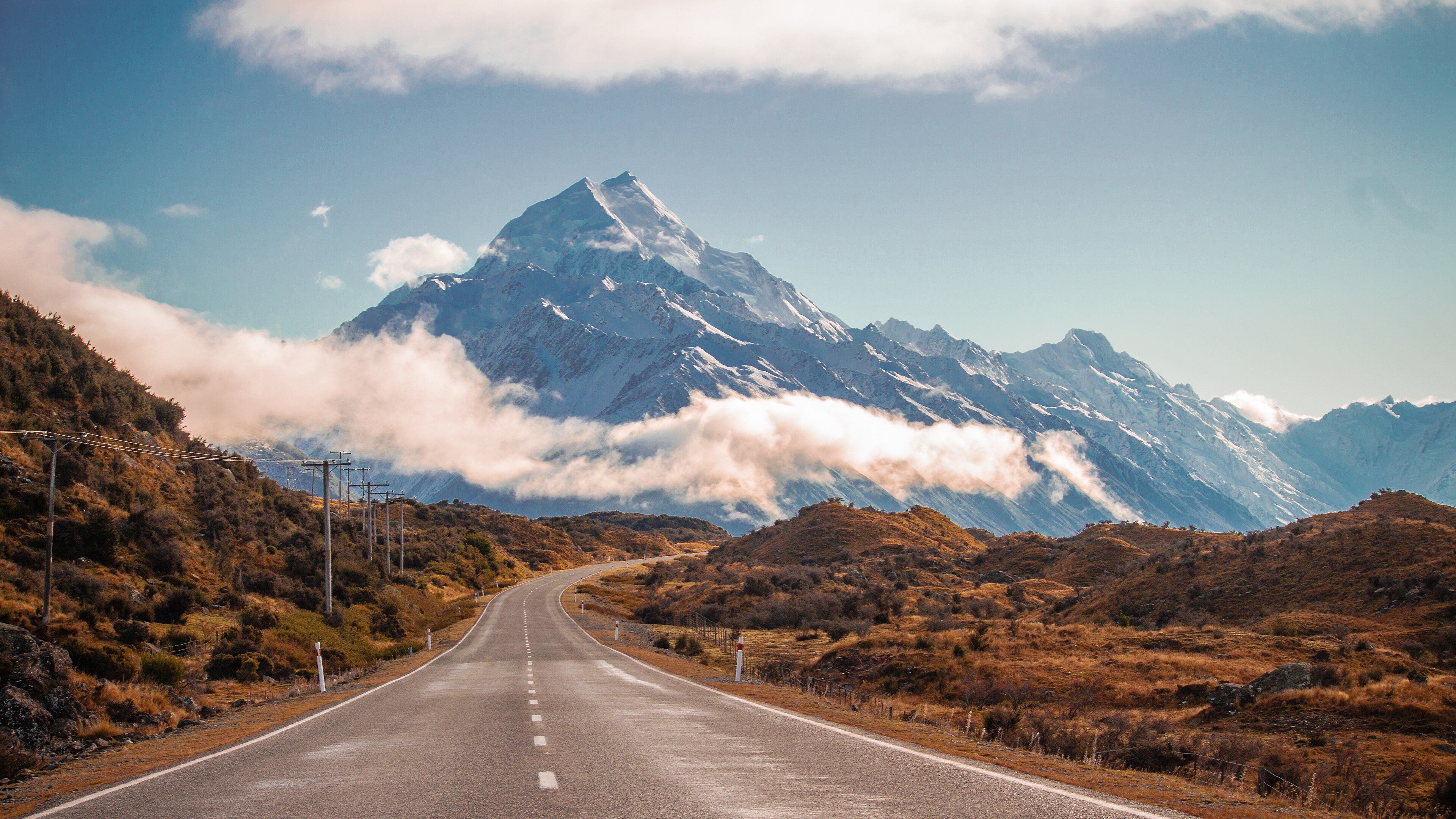 An empty road winding toward Mount Cook under a clear sky